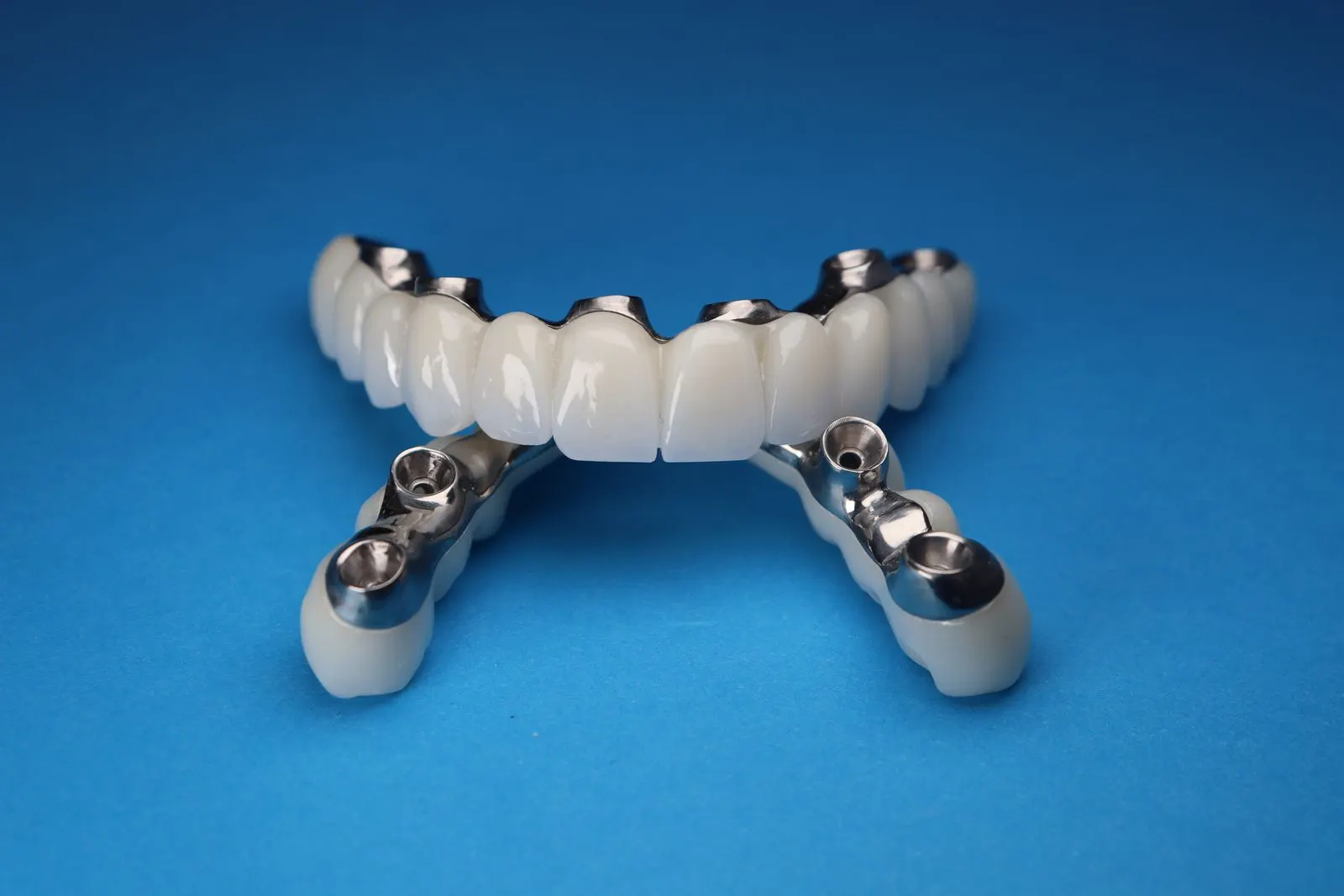Full-arch implant bridge on a blue background